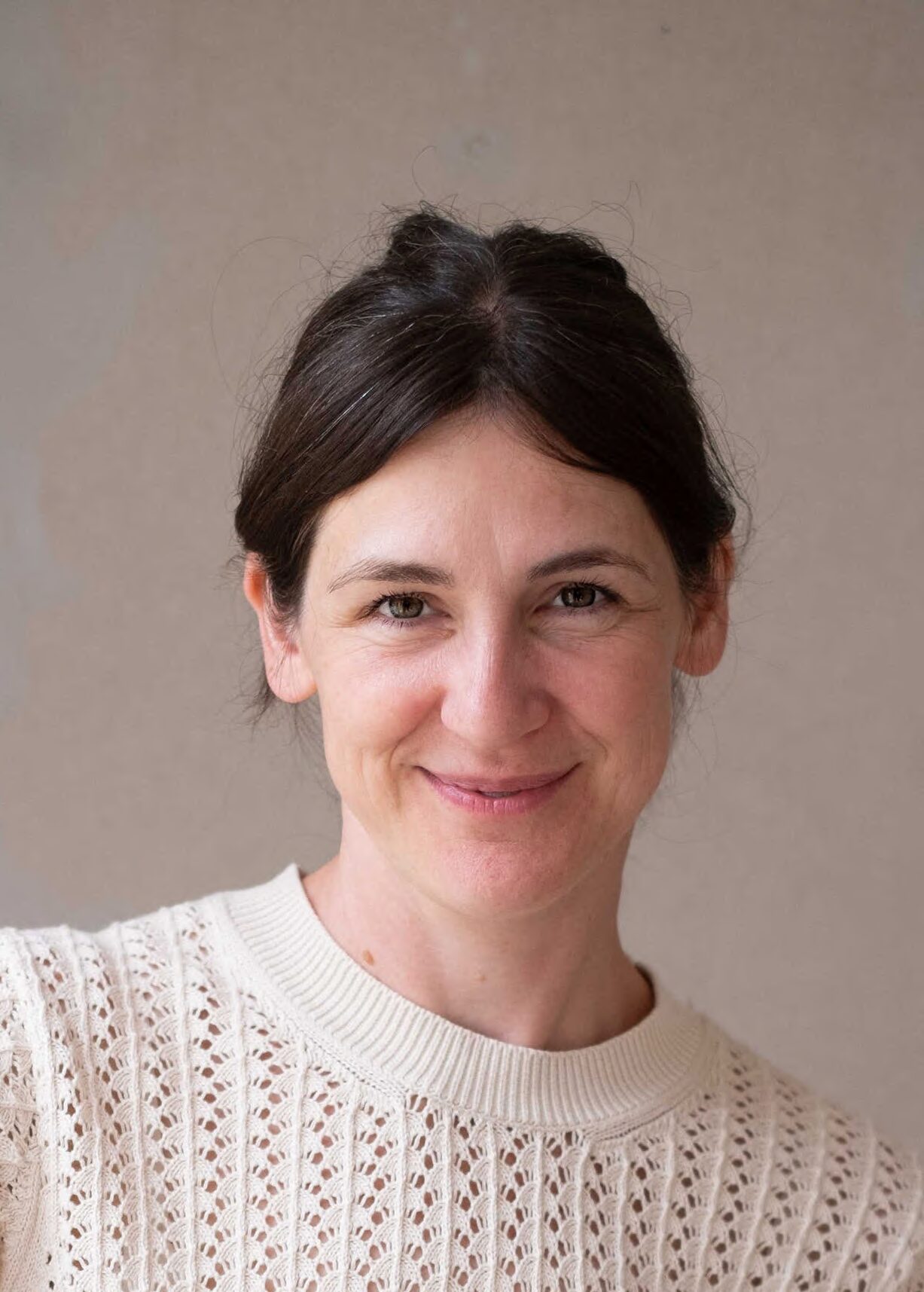 Portrait Dr. Jasmin Jossin vor beige-marmoriertem Hintergrund