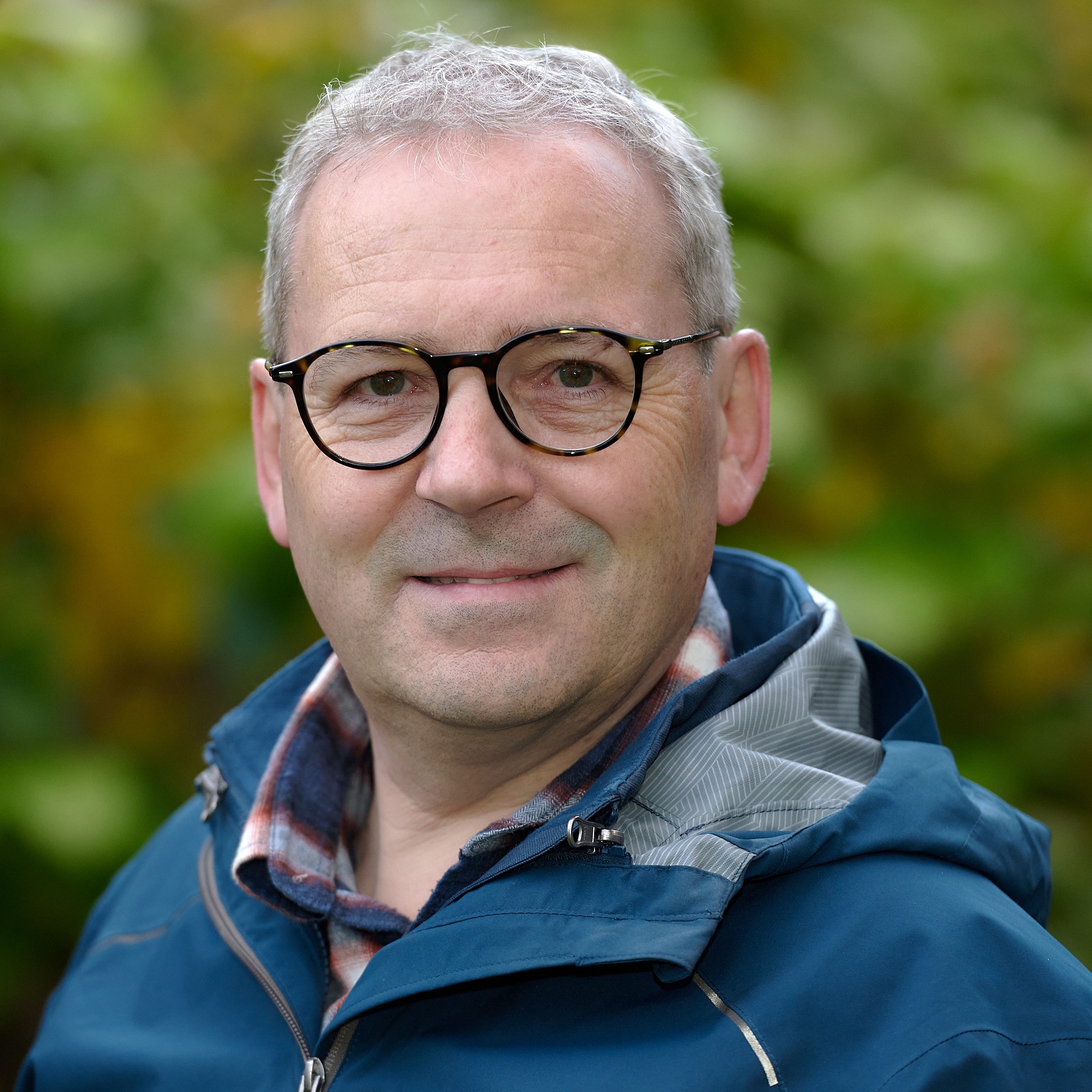 Portrait Michael Wiesner im Freien vor unterschiedlich grünem Hintergrund